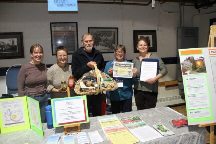 PHOTO COURTESY OF SITKA LOCAL FOODS NETWORK
TABLE OF THE DAY AWARD: Sitka Farmers Market manager Anastasia Stefanowicz, second from left, and Sitka Local Foods Network board treasurer Joel Hanson, center, present Callie Simmons, left; Barbara Bingham, fourth from left, and Leah Mason of Transition Sitka  with the Table of the Day Award for the sixth Sitka Farmers Market of the season; on Saturday, Sept. 9, at the Alaska Native Brotherhood Founders Hall. Transition Sitka (Hanson is president of the group) is